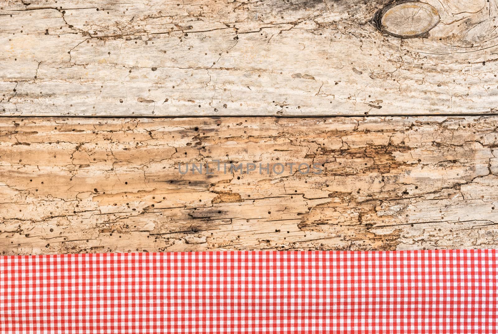 Rustic wooden table surface with red checkered cloth, top view