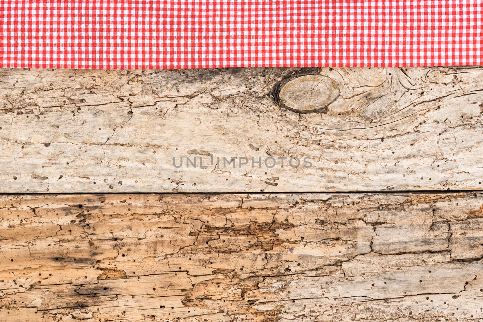 Rustic wooden table surface with red checkered cloth, top view