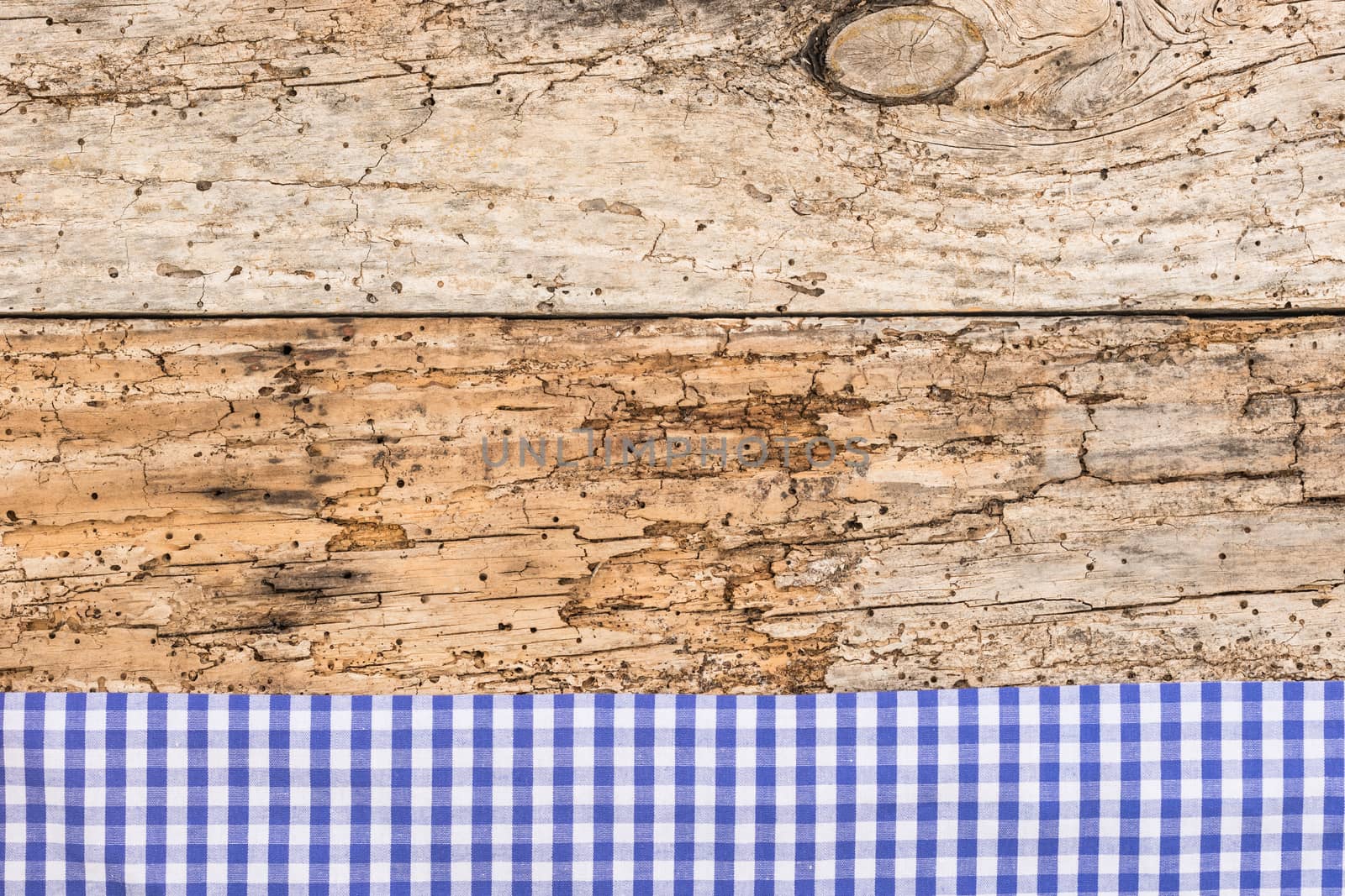 Rustic wooden table surface with blue checkered cloth, top view