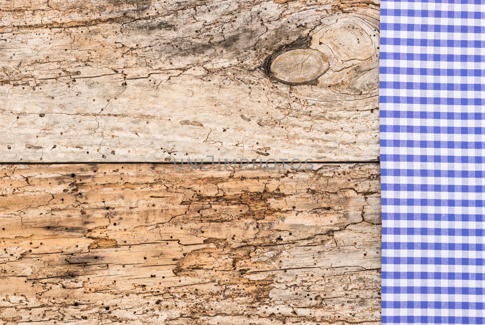 Blue checked tablecloth on rustic wooden table background, top view