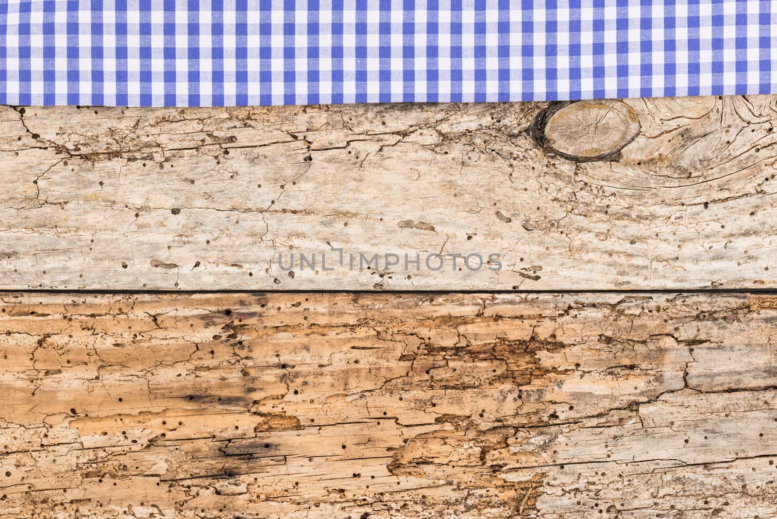 Rustic wooden table surface with blue checkered cloth, top view