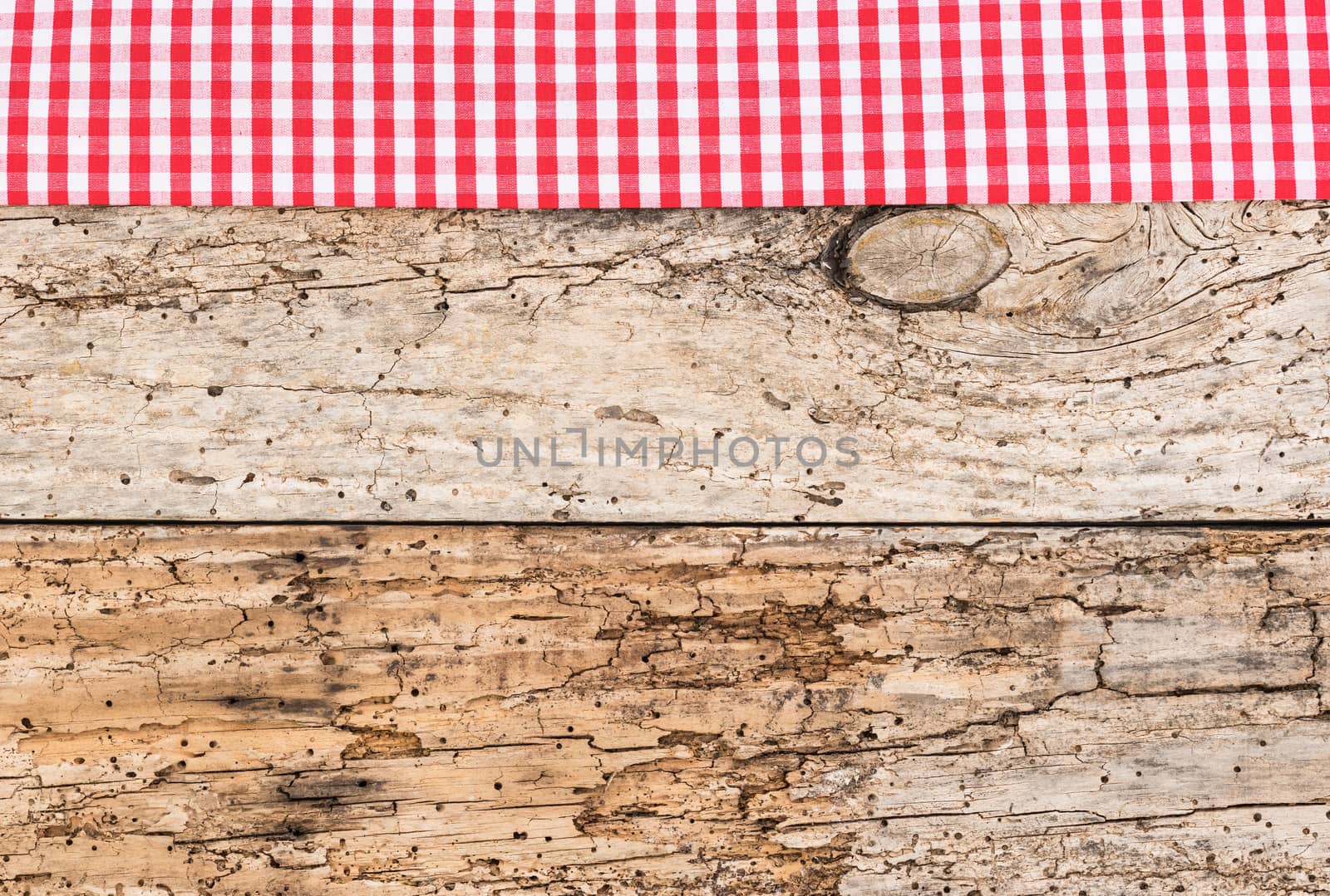 Rustic wooden table surface with red checkered cloth, top view