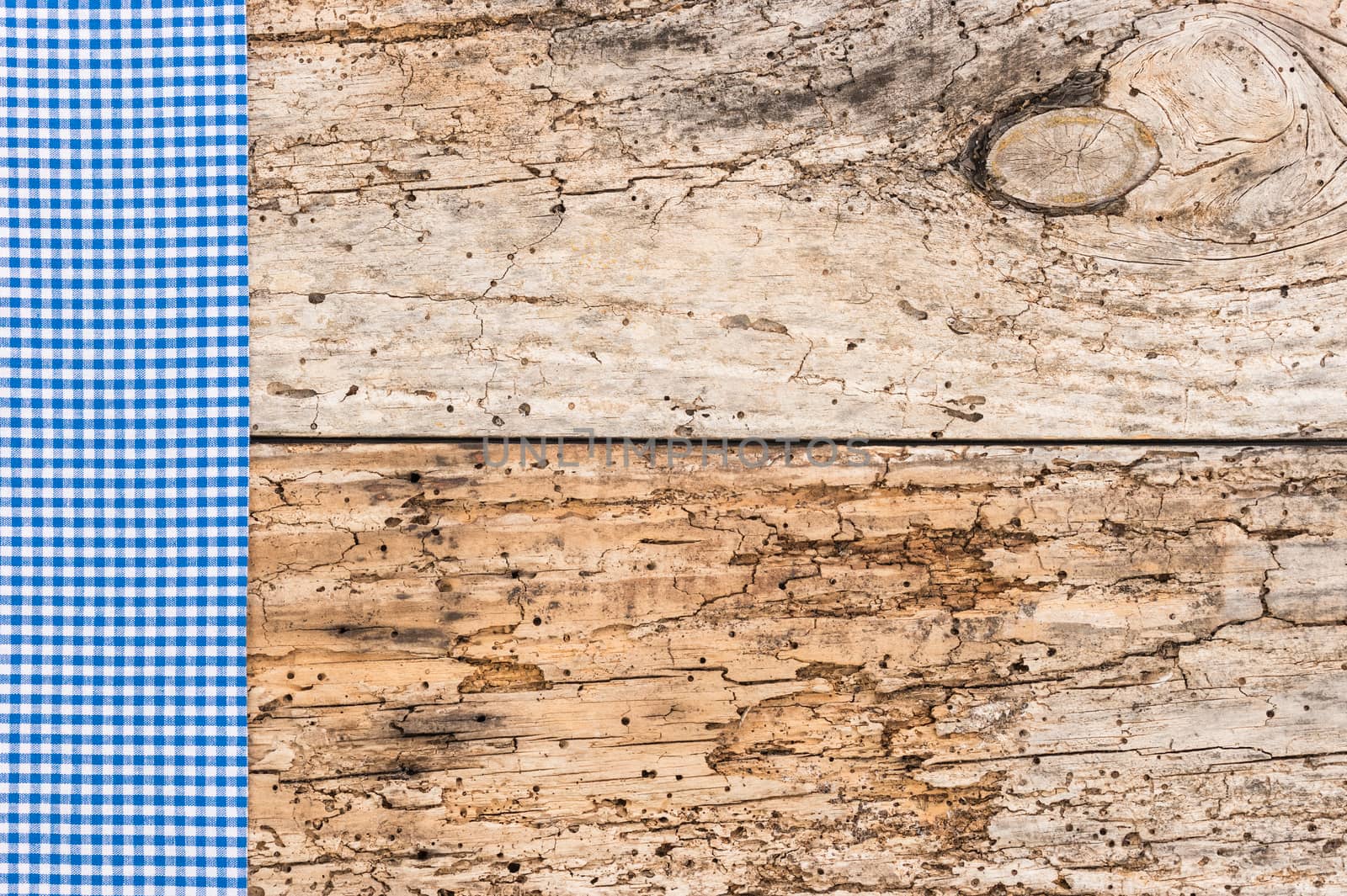 Blue checkered tablecloth on rustic wooden table background