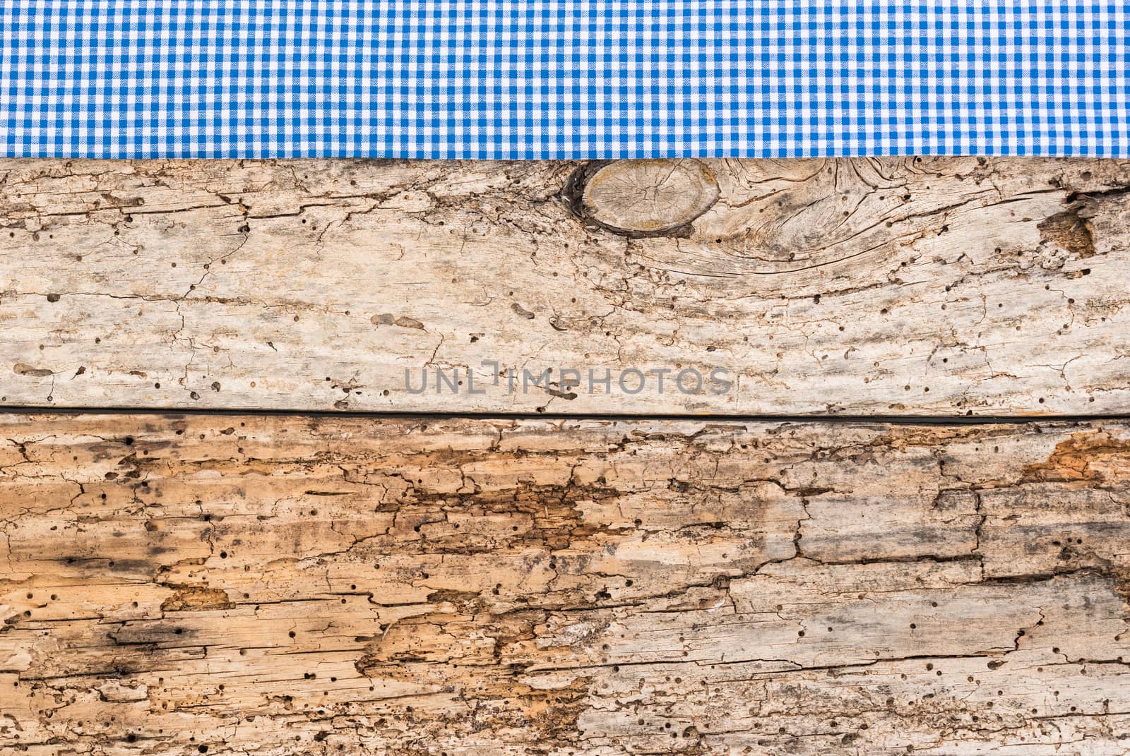 Rustic wooden table surface with blue checkered cloth, top view