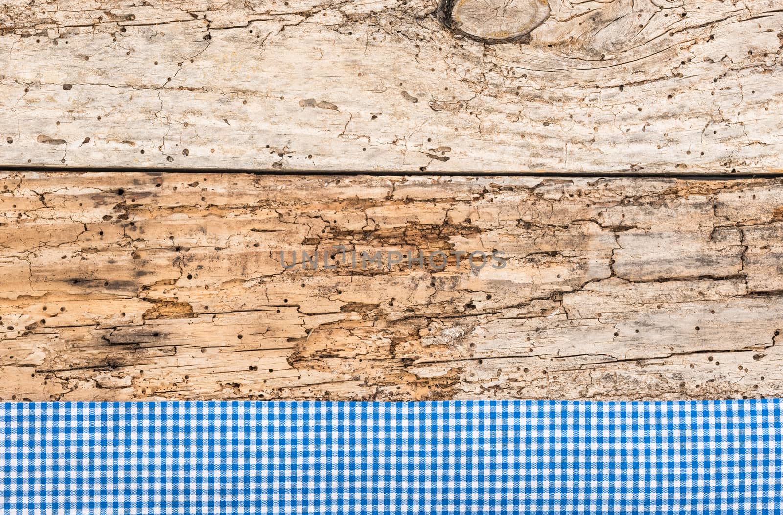 Rustic wooden table surface with blue checkered cloth, top view