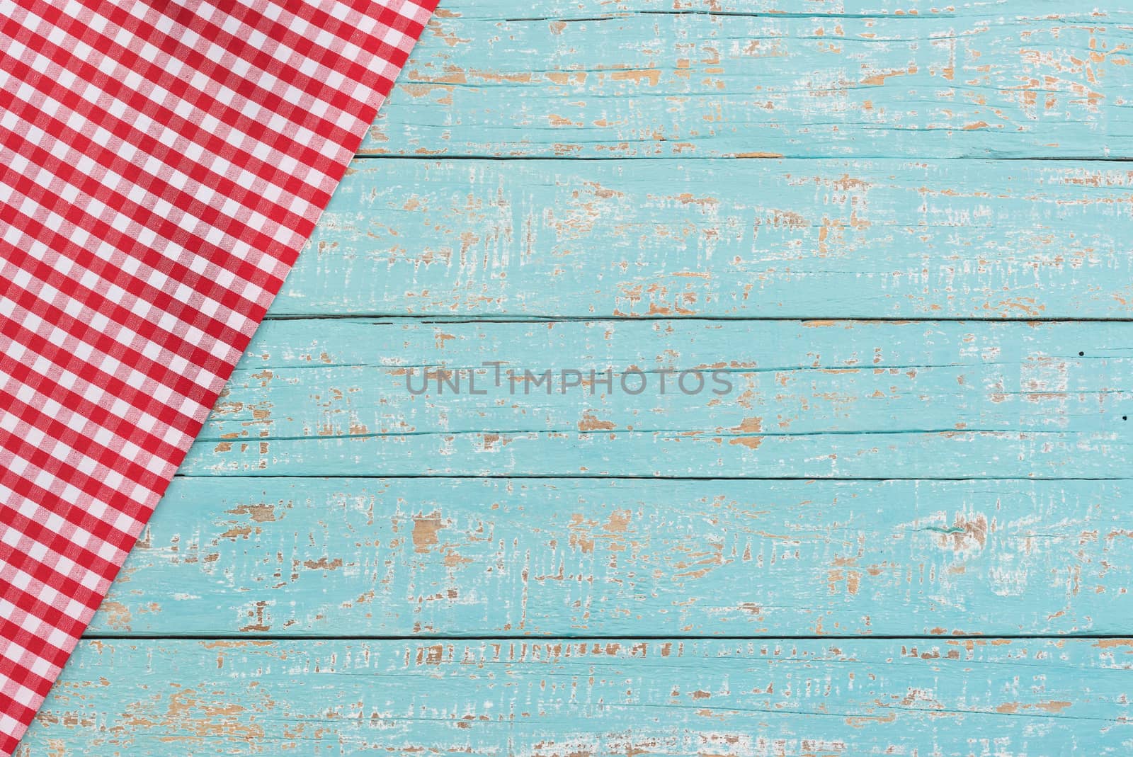 Red checkered tablecloth on rustic blue wooden table background
