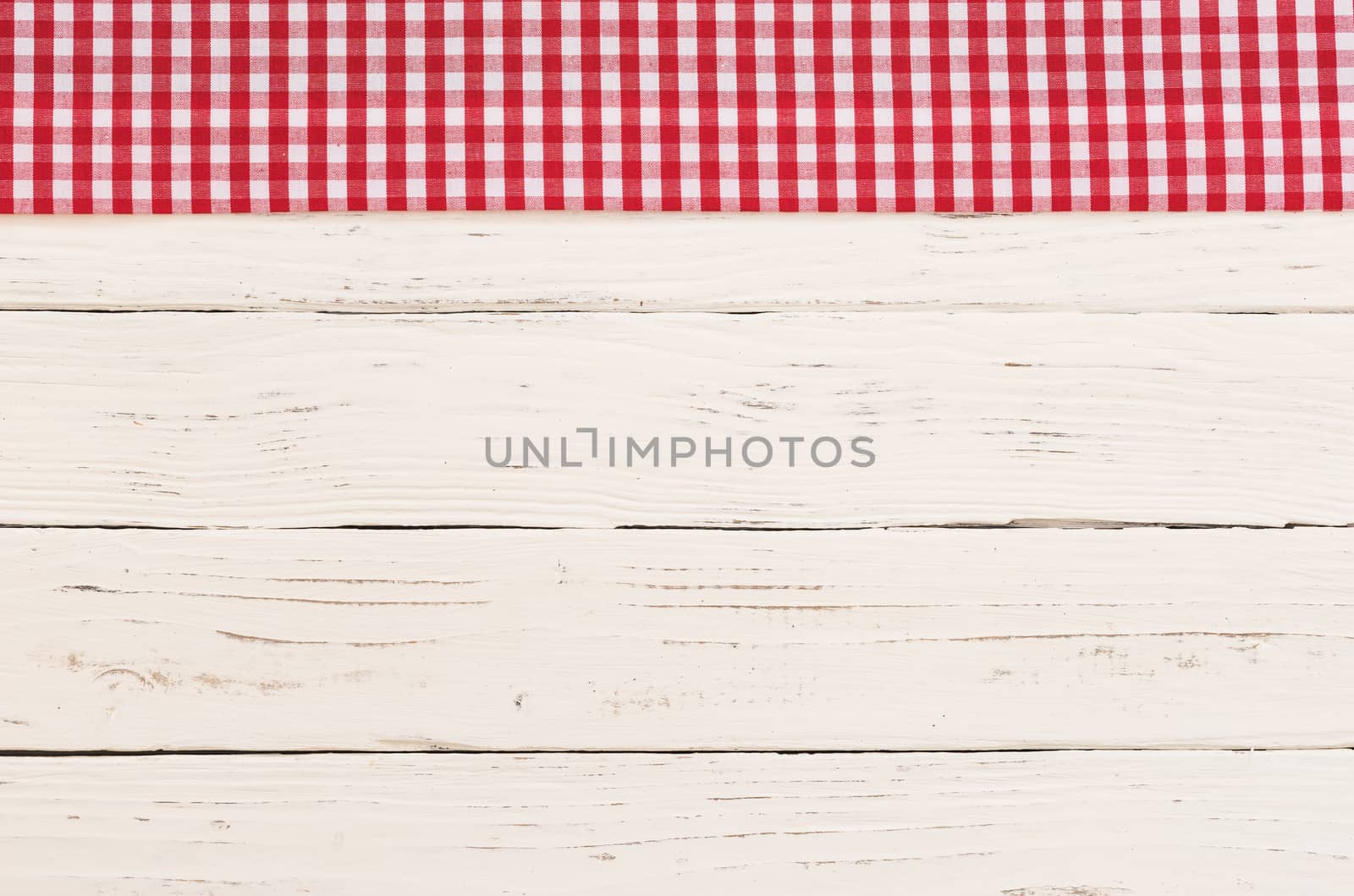 Red checkered tablecloth on rustic white wooden table background