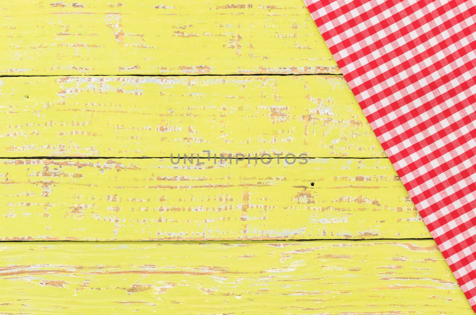 Rustic yellow kitchen table background with red checked tablecloth