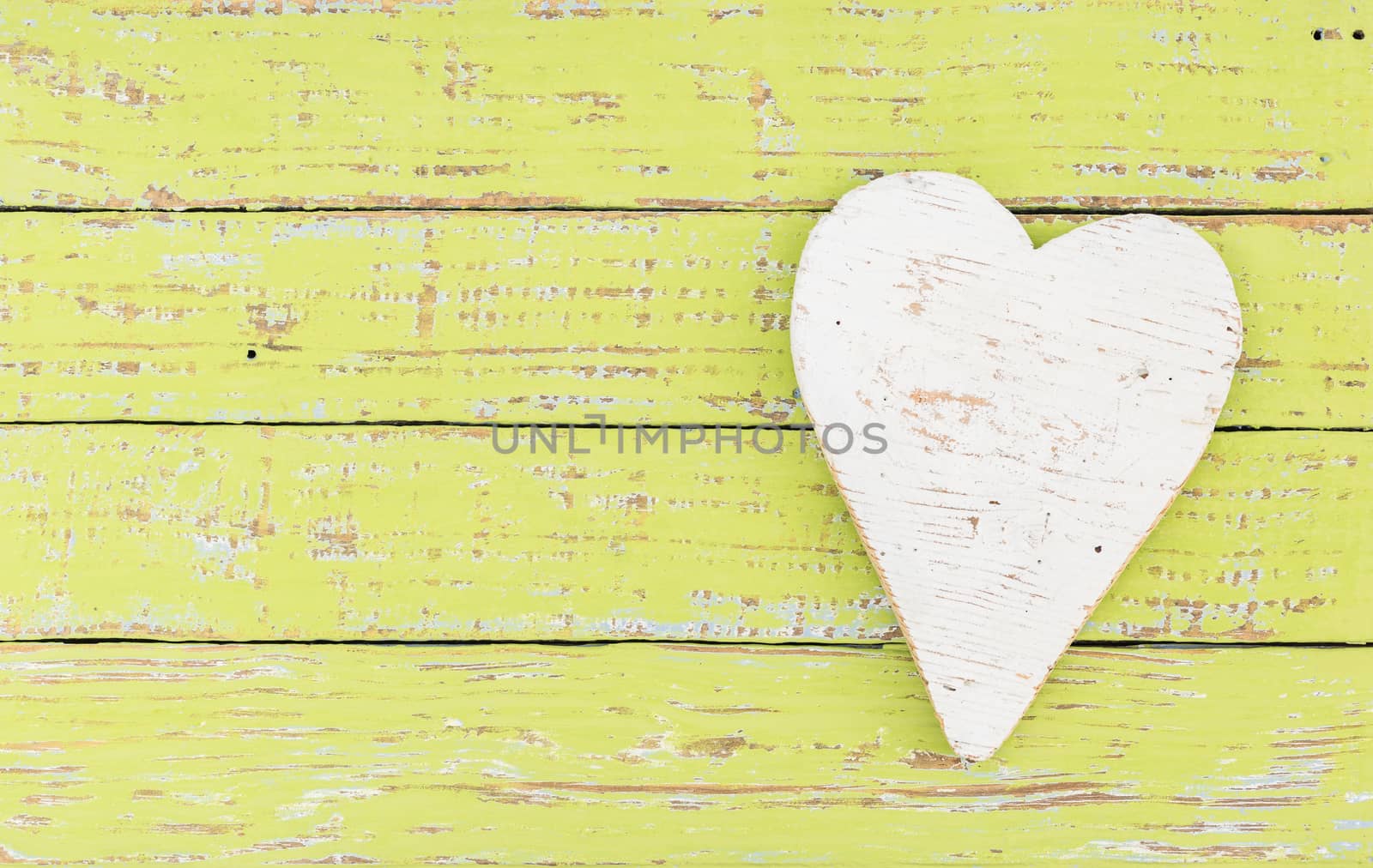 White wooden heart on green wood background with copy space