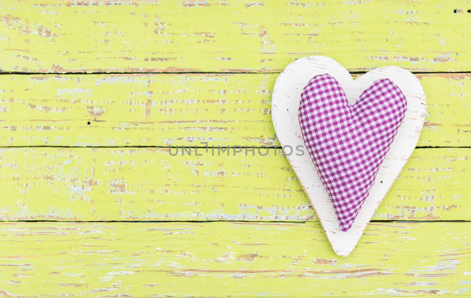 Fabric purple heart on green wooden background with copy space