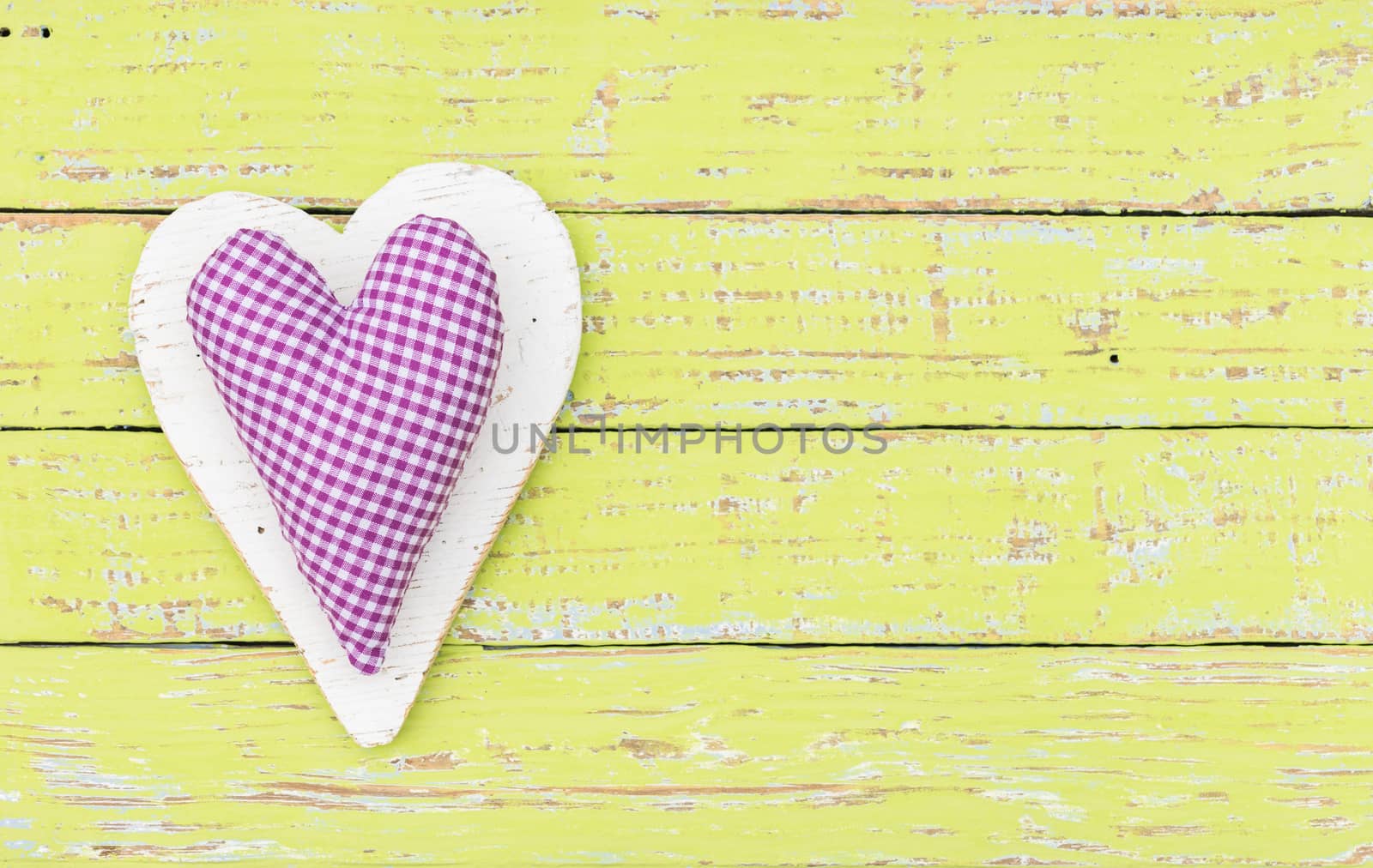 Rustic fabric heart on yellow wood background with copy space