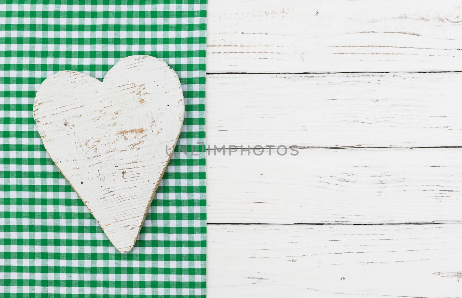 White heart on green fabric and white wood background by Vulcano
