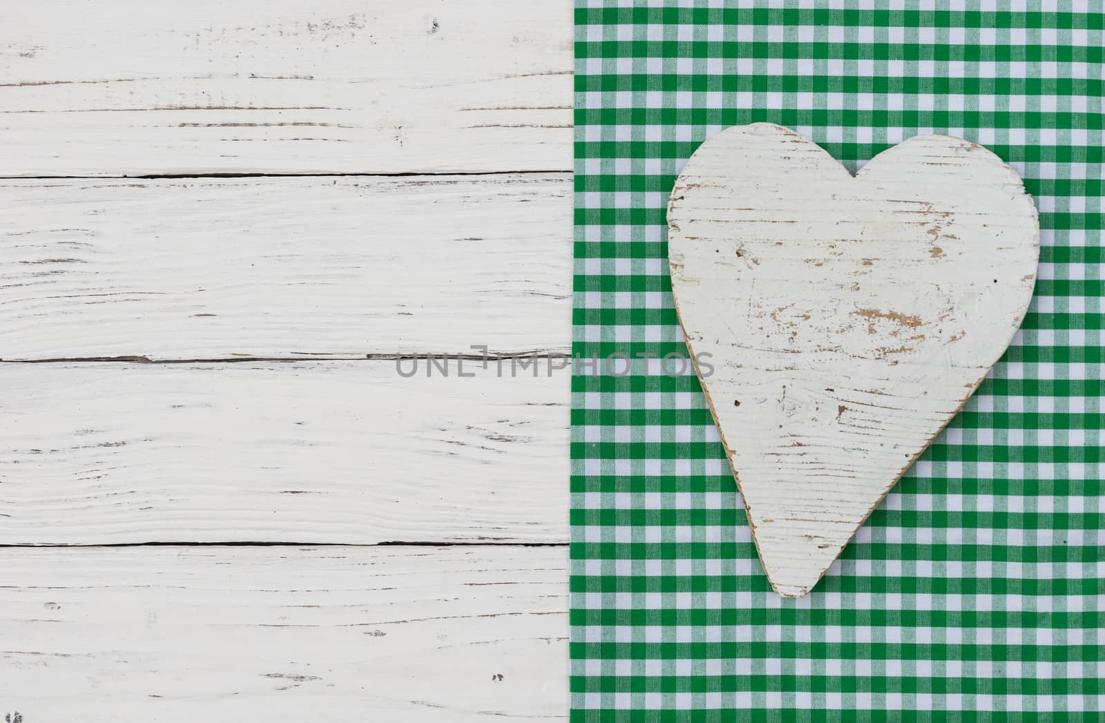 White wooden heart on green textile border and background with copy space