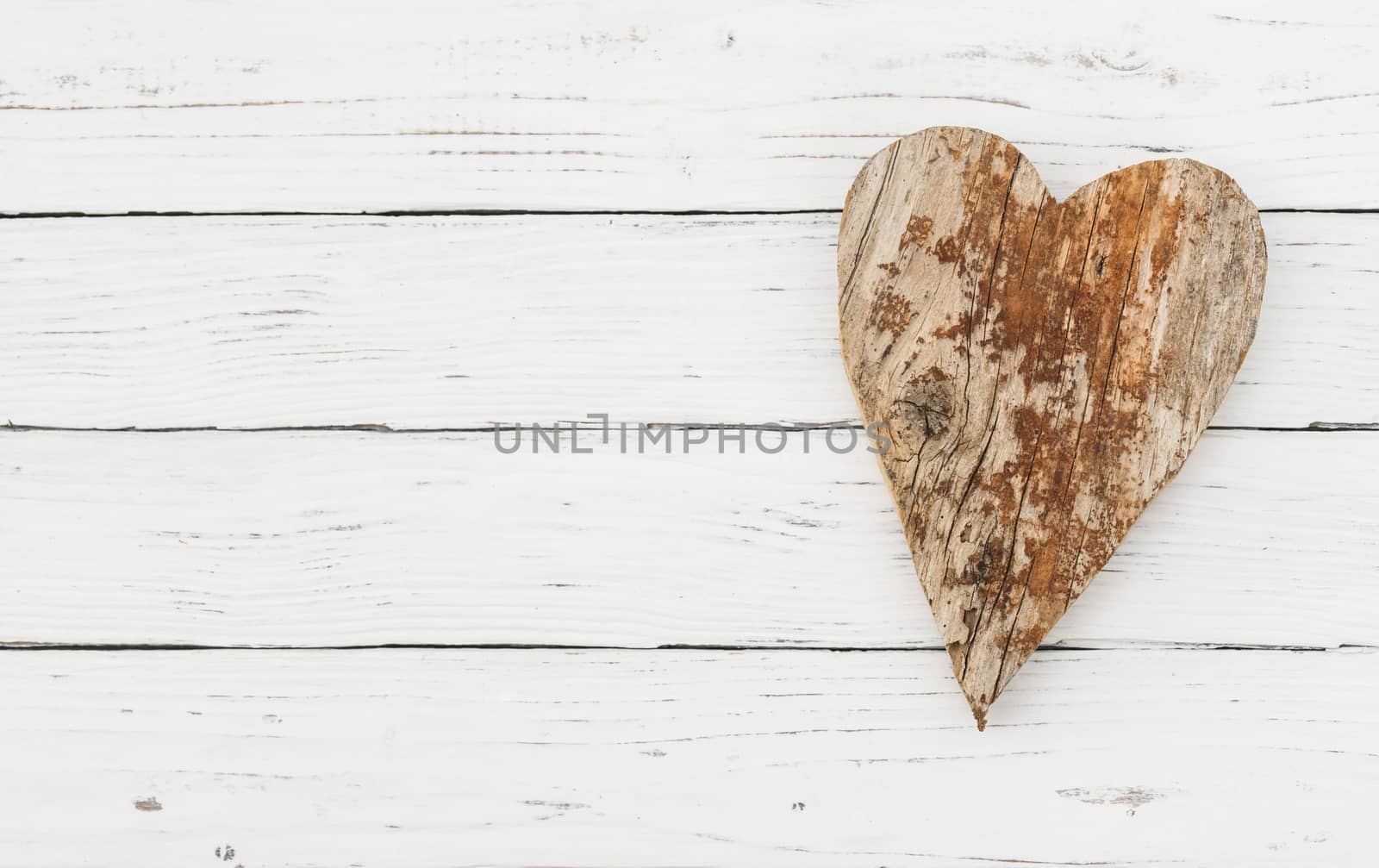 Brown wooden heart shape on white wood background with copy space