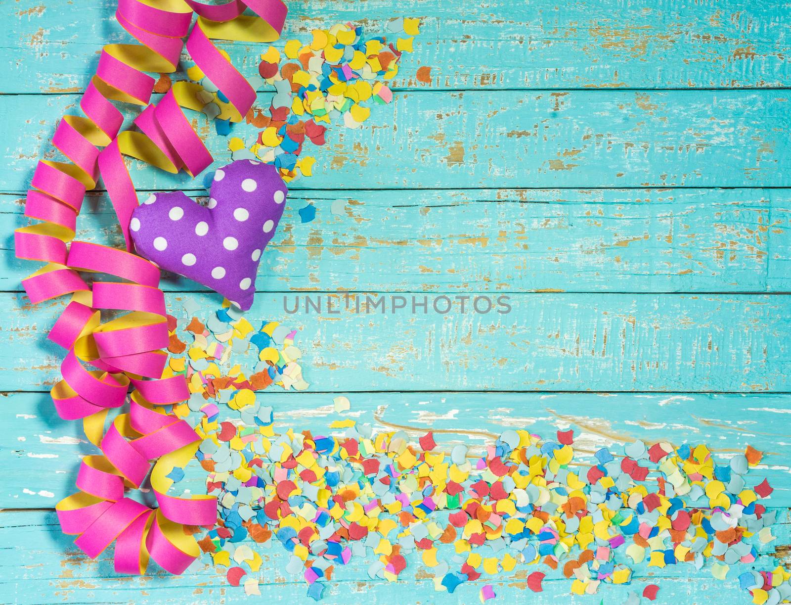 Streamers, confetti and heart decoration on blue wood background for party or birthday celebration