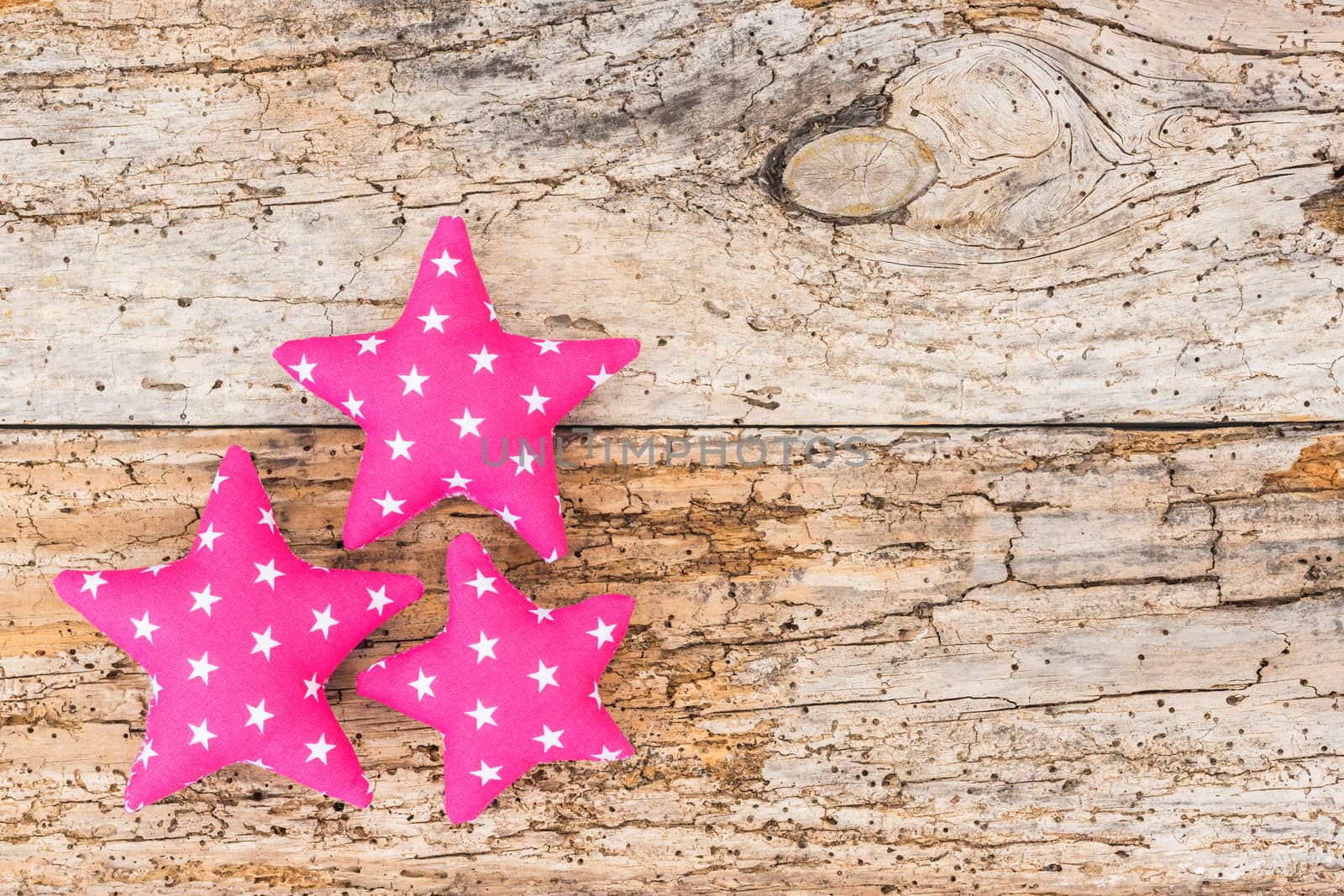 Three pink fabric stars on old wooden background with copy space