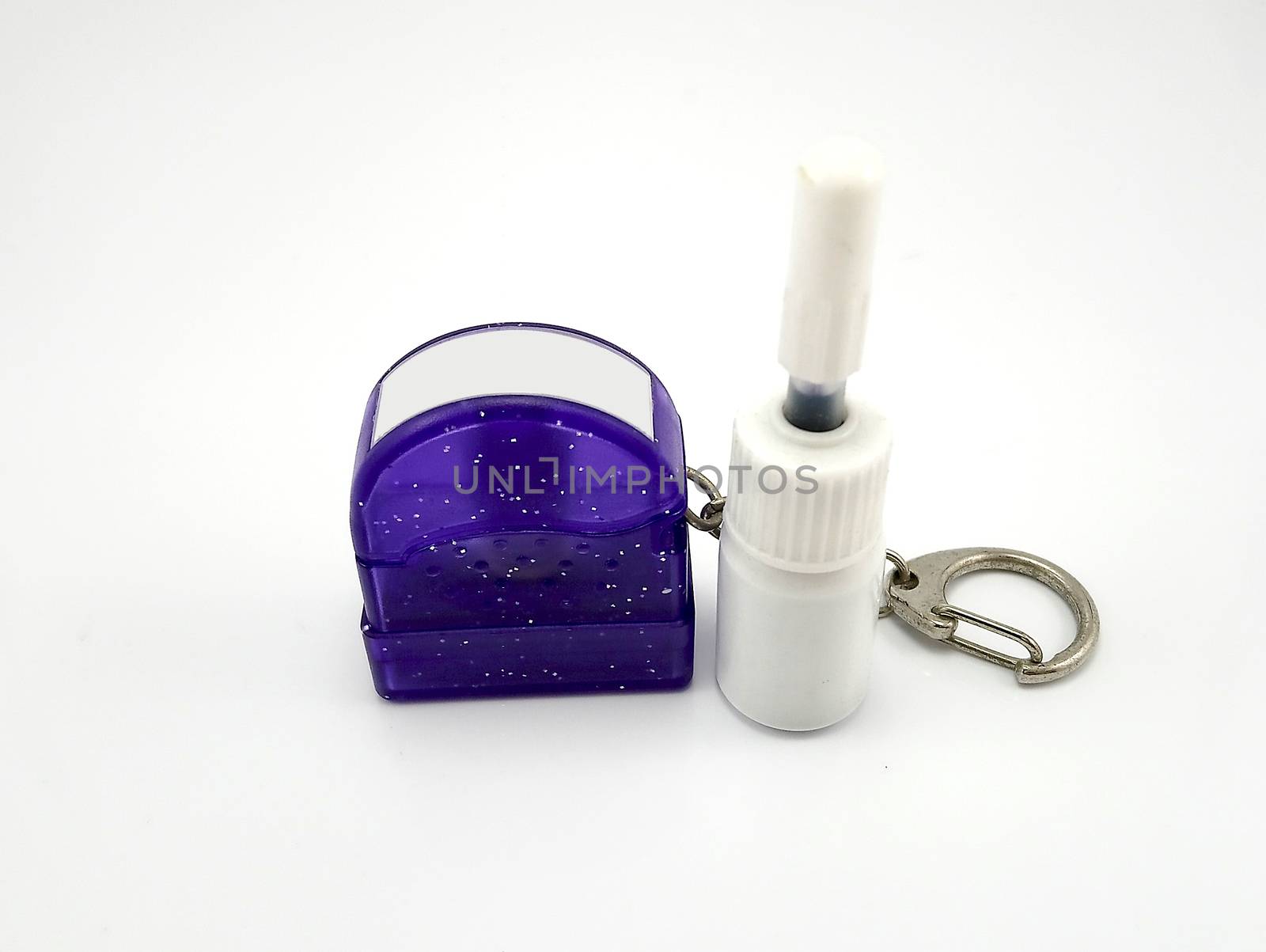 Liquid black refill ink placed in small white plastic bottle and Small purple plastic glitters stamp with metal key ring use to stamp on paper
