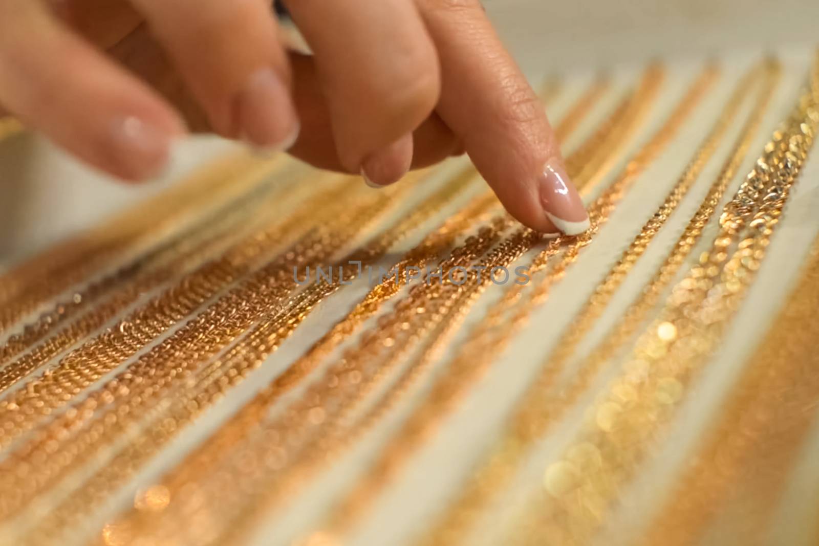 The woman chooses the golden chain with her index finger.