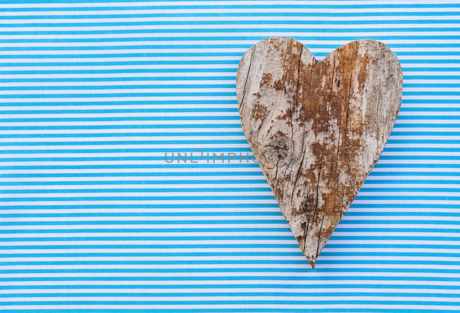 Handmade wooden heart shape on blue fabric background with copy space