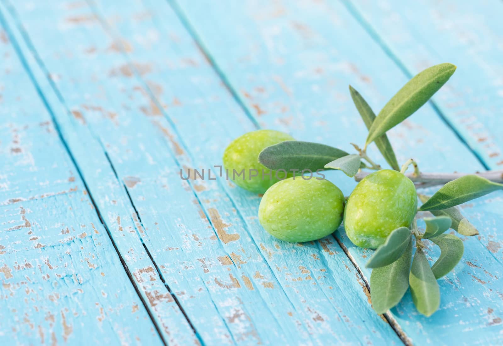 Fresh green olives on blue wood background