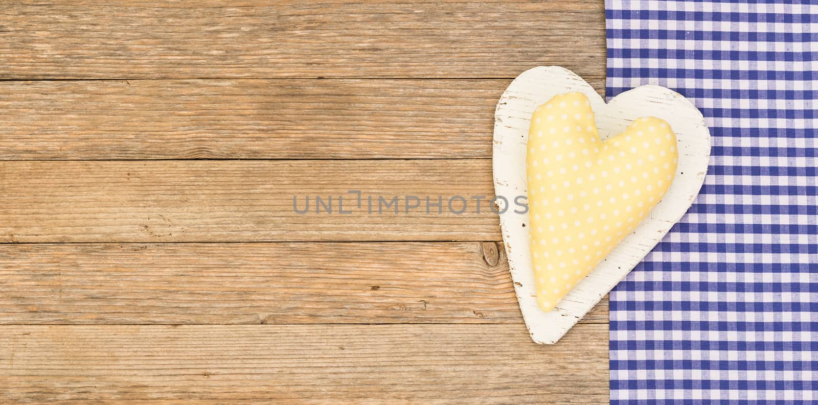 Yellow fabric heart on blue textile frame and wood background with copy space