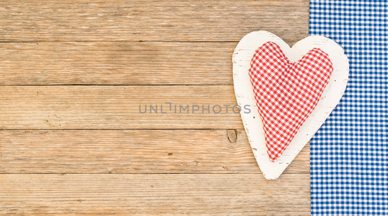 Rustic red fabric heart on blue frame and wooden background