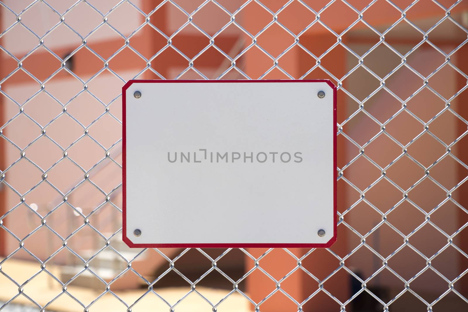 The white metal sign is installed on the metal mesh fence. by Eungsuwat