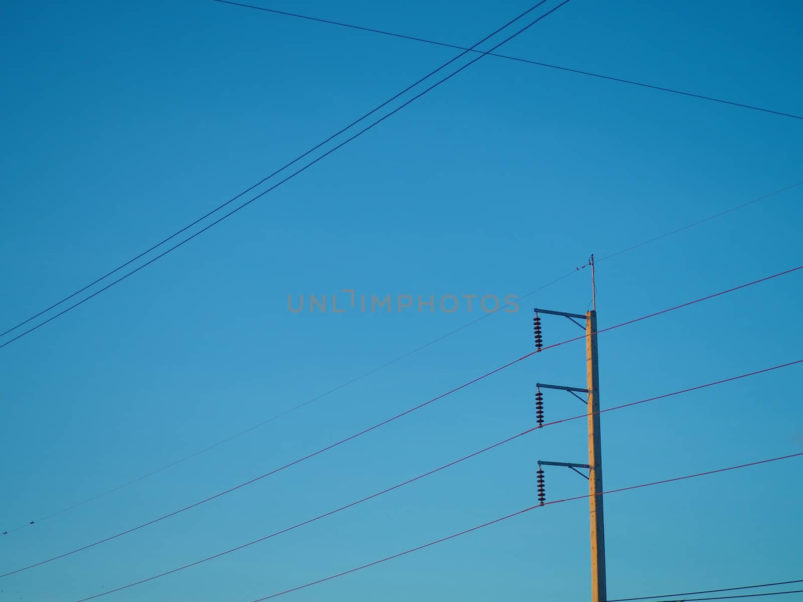 The high voltage light pole fastened to multiple wires leading to On the background is a blue sky.
Minimal concept and energy.