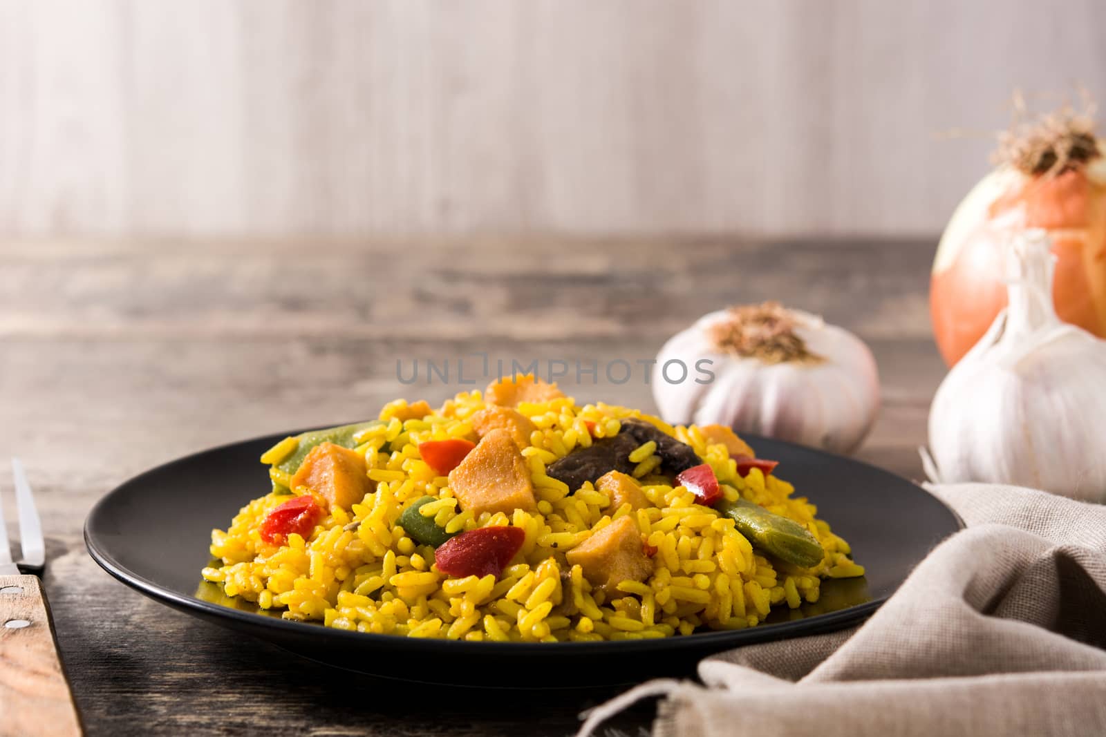 Fried rice with chicken and vegetables on black plate on wooden table