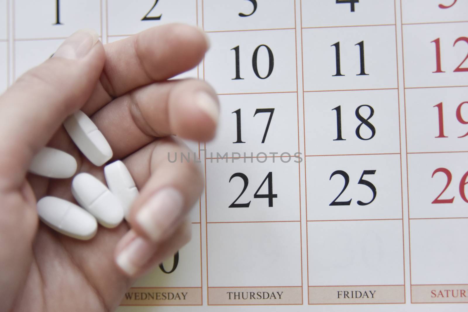 selective focus at pills and calendar with blurry hand. schedu;ed treatment concept