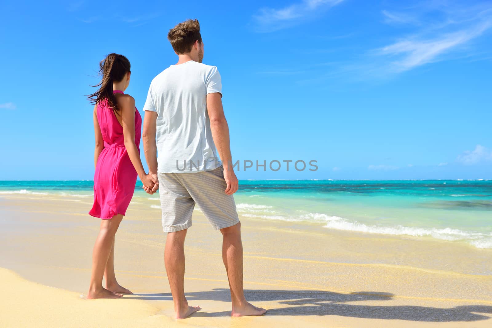 Beach couple looking at ocean view from behind by Maridav