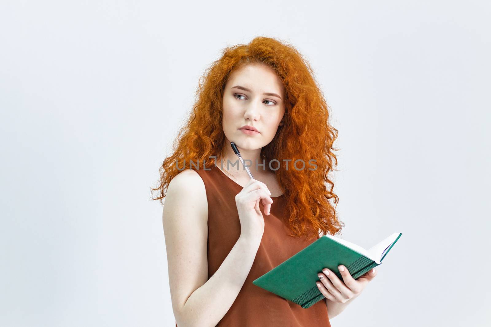 Let me think. A Studio shot of a pretty red-haired girl looking sideways with a thoughtful and sly expression on her face, as if she had a good idea planning something. home quarantine