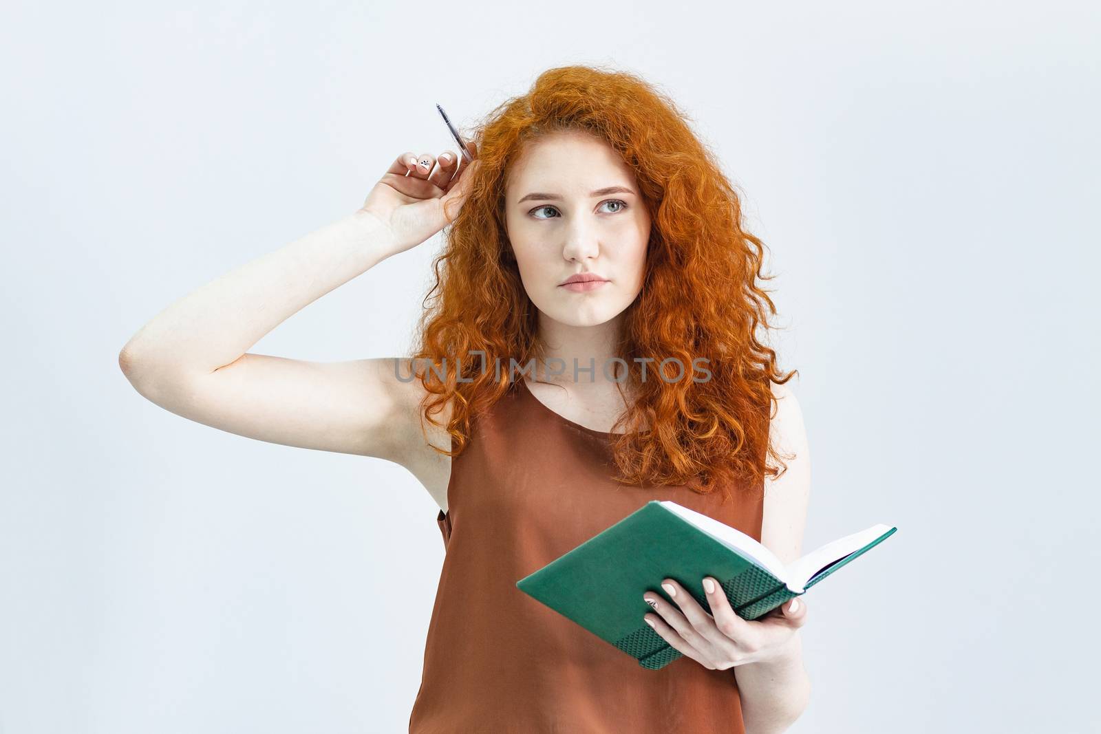 Let me think. A Studio shot of a pretty red-haired girl looking sideways with a thoughtful and sly expression on her face, as if she had a good idea planning something. home quarantine