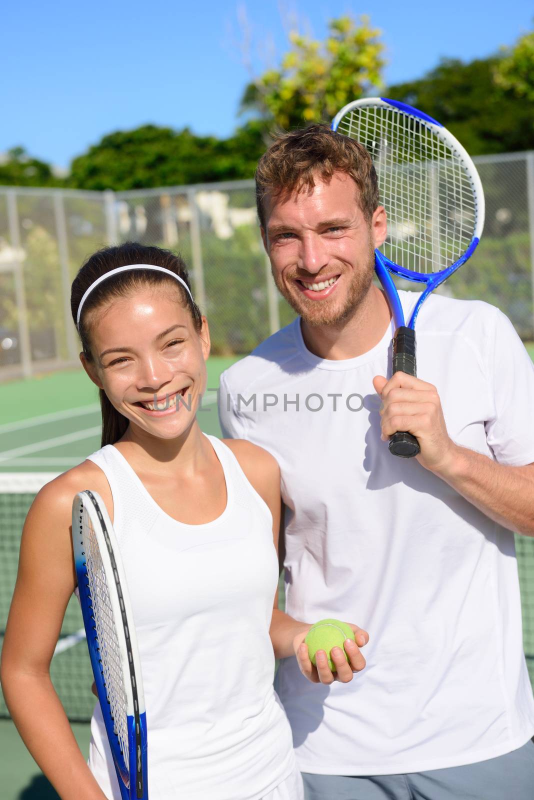 Tennis sport - Mixed doubles couple players portrait relaxing after playing game outside in summer. Happy smiling people on outdoor tennis court living healthy active lifestyle. Woman and man athletes