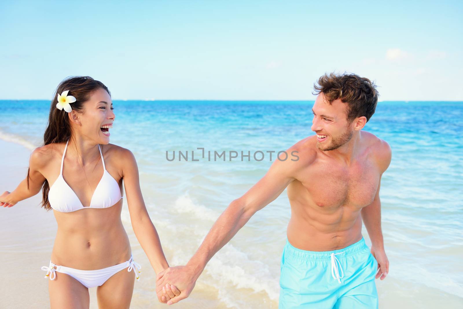 Beach couple having fun happy on beach vacation by Maridav