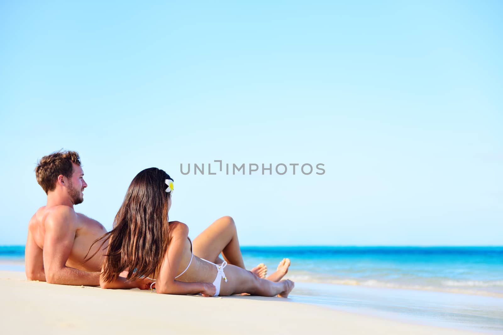 Beach vacation couple relaxing tanning in summer by Maridav