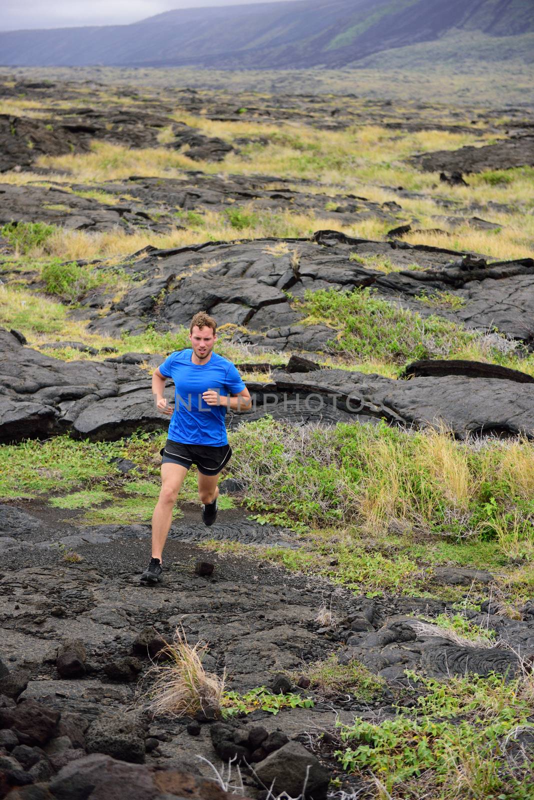 Trail Running fitness male ultra runner in nature landscape, volcanic rocks. Sport running man in cross country trail run. Male athlete exercising and training in summer outdoors.