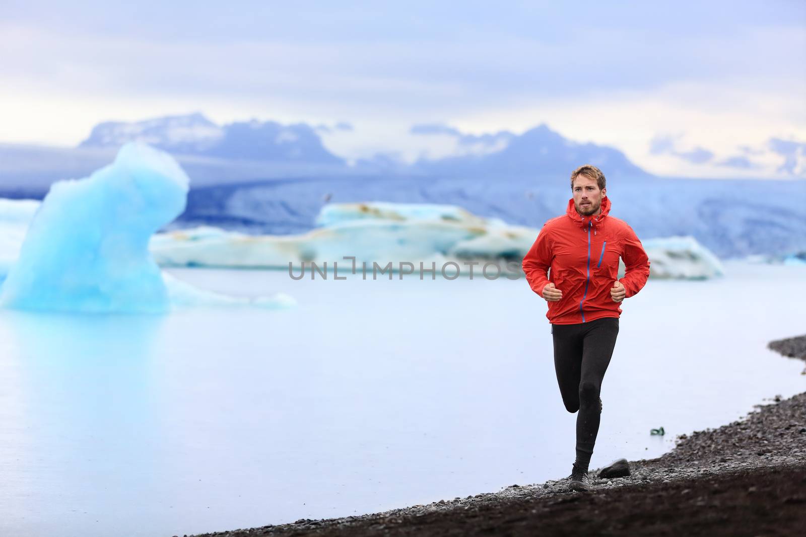 Running man. Trail runner training for marathon run in beautiful nature landscape. Fit male athlete jogging and cross country running by icebergs in Jokulsarlon glacial lake in Iceland.