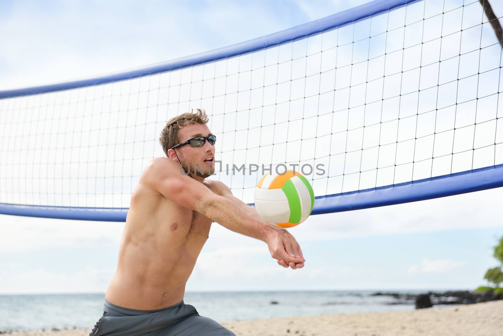 Beach volleyball man playing game hitting forearm pass volley ball during match on summer beach. Male model living healthy active lifestyle doing sport on beach.