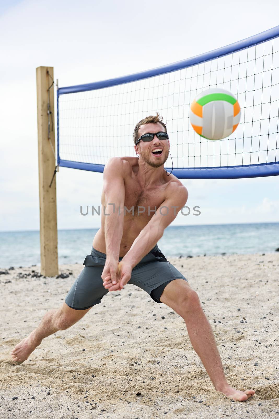 Man playing beach volleyball game hitting ball by Maridav