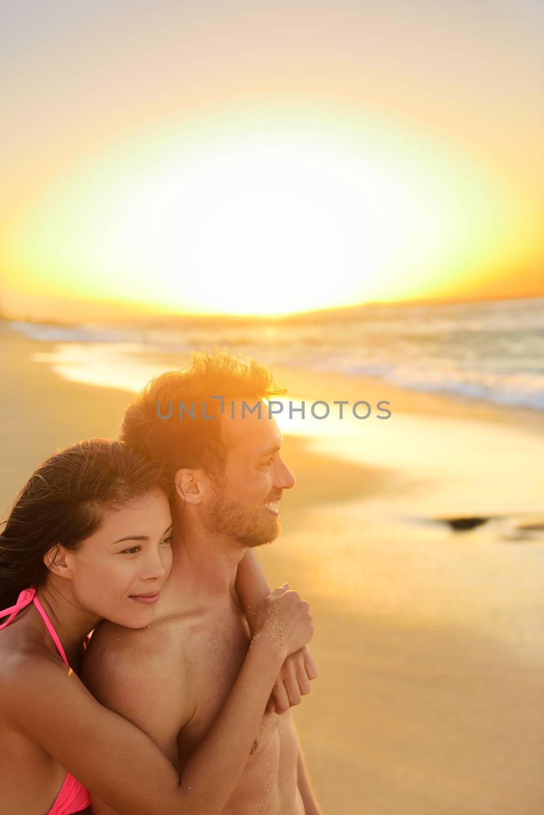 Happy romantic couple lovers on beach honeymoon having playful fun together during summer beach holidays. Cheerful young multiracial couple, Asian woman and Caucasian man. From Oahu, Hawaii, USA.
