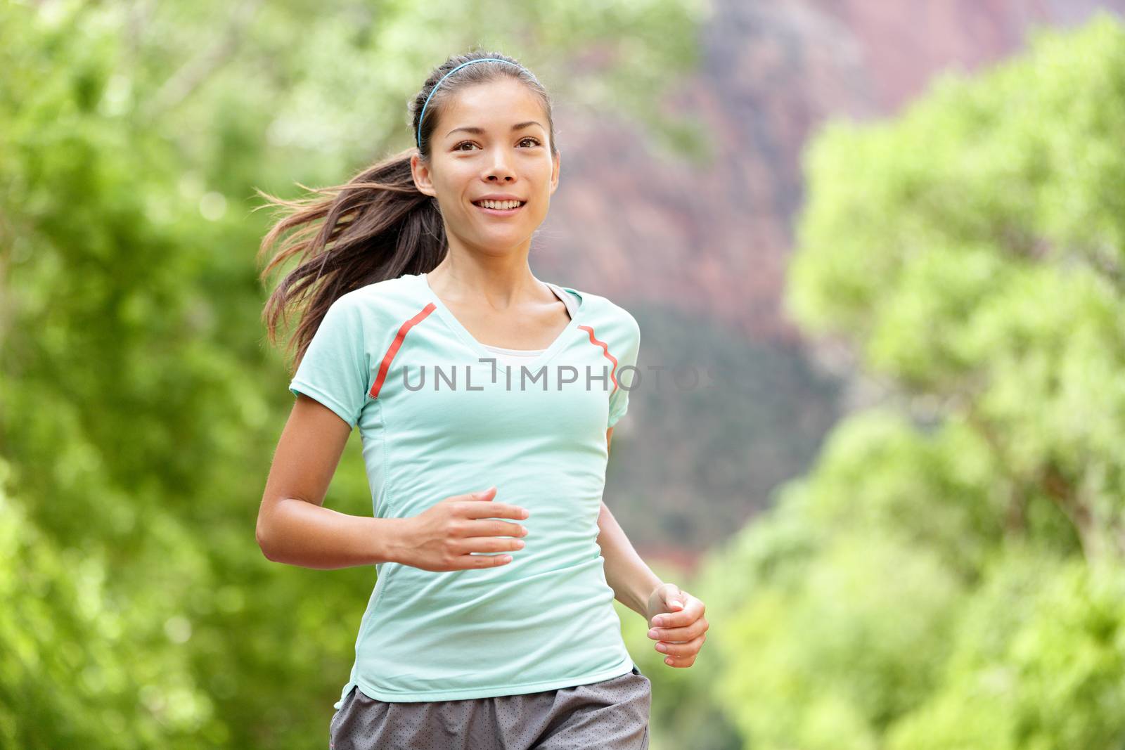 Woman runner running training living healthy fitness sport lifestyle. Active female athlete jogging outside smiling happy with aspirations. Beautiful young mixed race Asian Caucasian girl in her 20s.