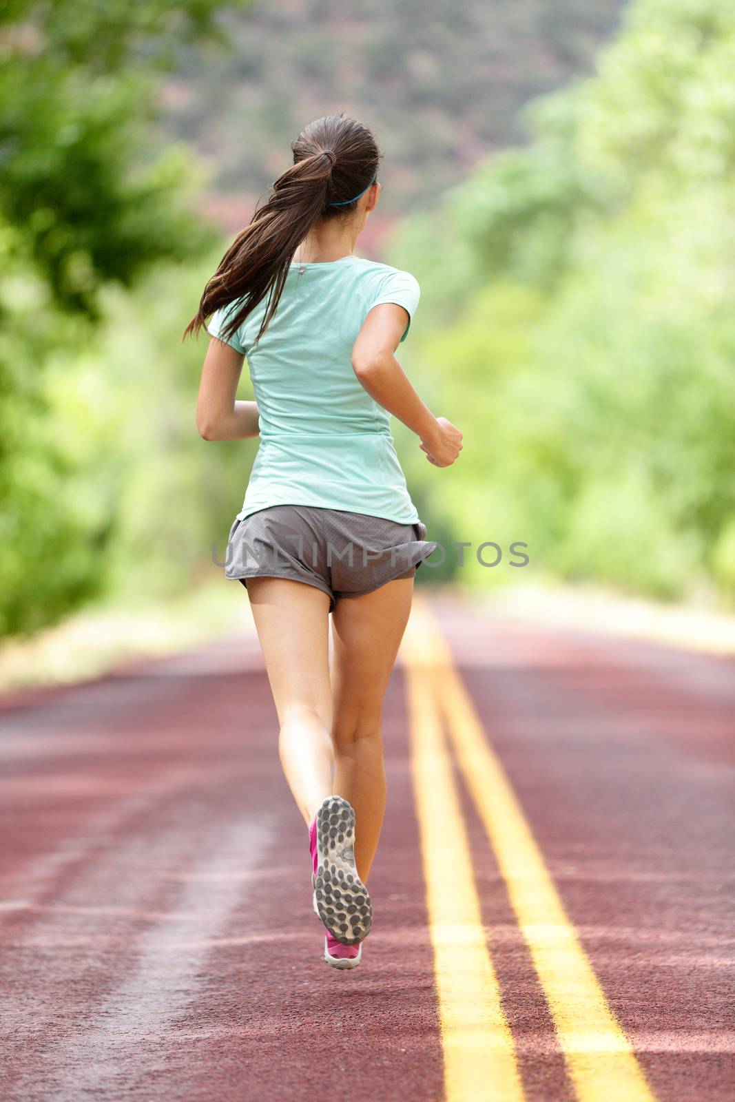 Young lady working out running away on rural road by Maridav