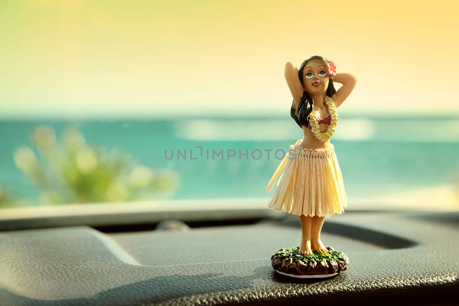 Hula dancer doll on Hawaii car road trip. Doll dancing on the dashboard in front of the ocean. Tourism and Hawaiian travel freedom concept.