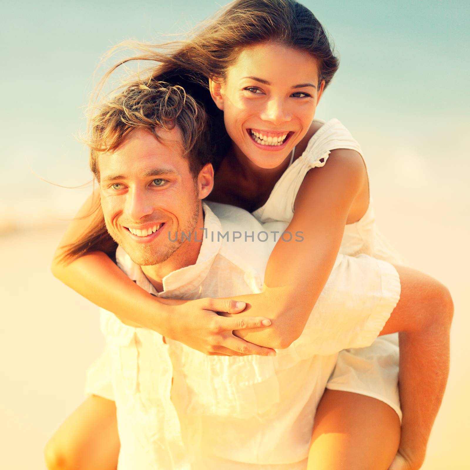 Romantic couple having fun piggyback on beach by Maridav