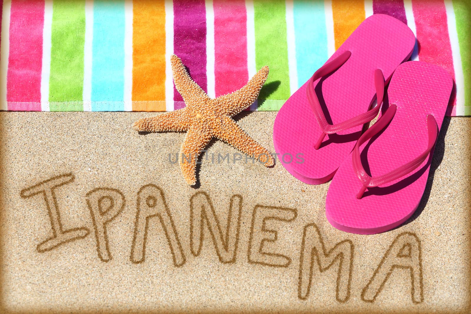 Ipanema beach concept. Overhead view ot the word RIO written on golden sand with a starfish, pink flip flops and towel conceptual of a summer vacation and travel in Rio de Janiero, Brazil