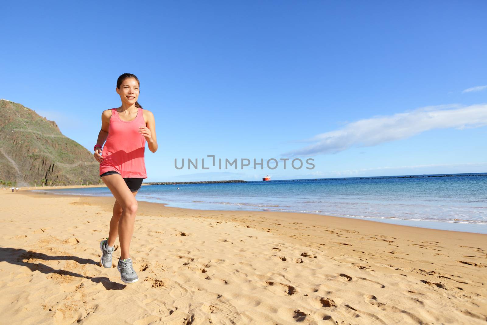 Jogging sports athlete runner woman running on beach sweating. Fit exercising female fitness model working out training for marathon run. Biracial Asian Caucasian sports girl.