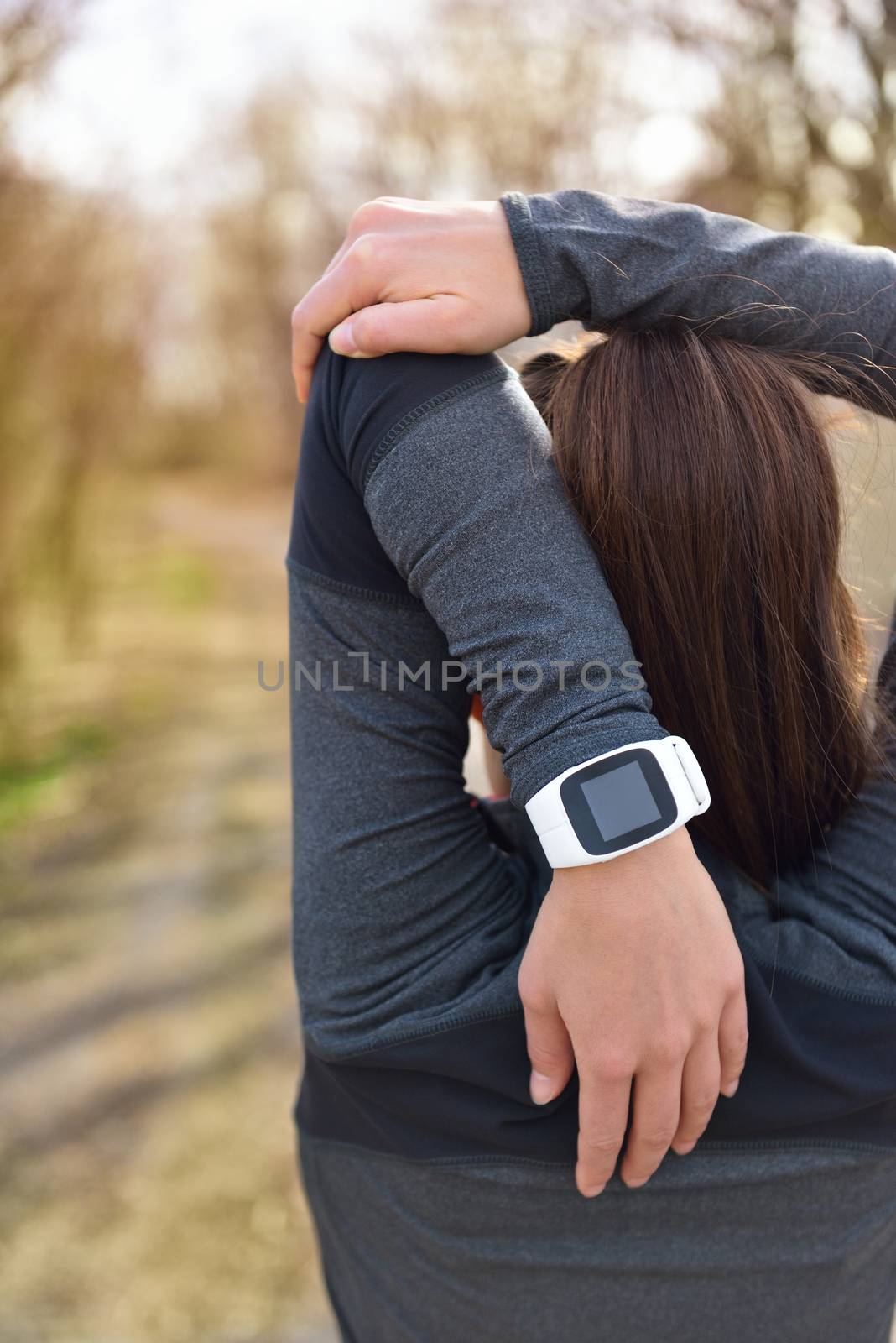 Smartwatch woman running with heart rate monitor. Closeup of female wrist wearing smart sport watch as activity tracker outdoors during cardio workout. Fitness girl stretching triceps during workout.