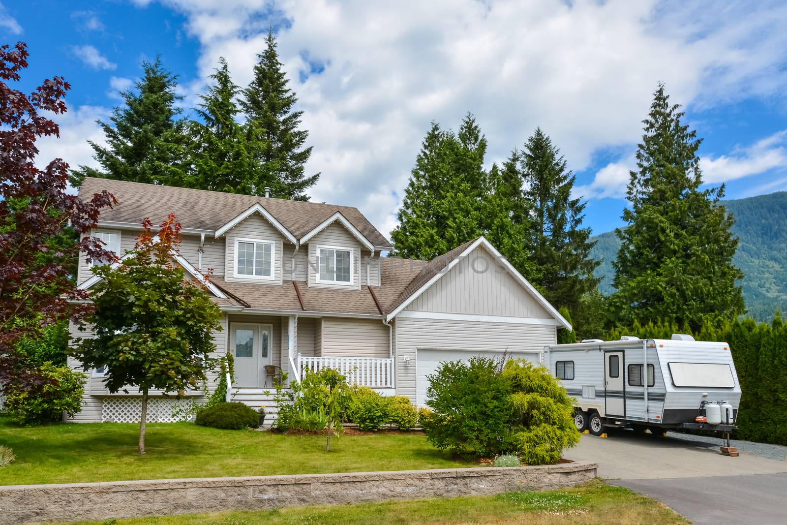 Big residential house with RV trailer parked on driveway. Family house on country side in British Columbia, Canada
