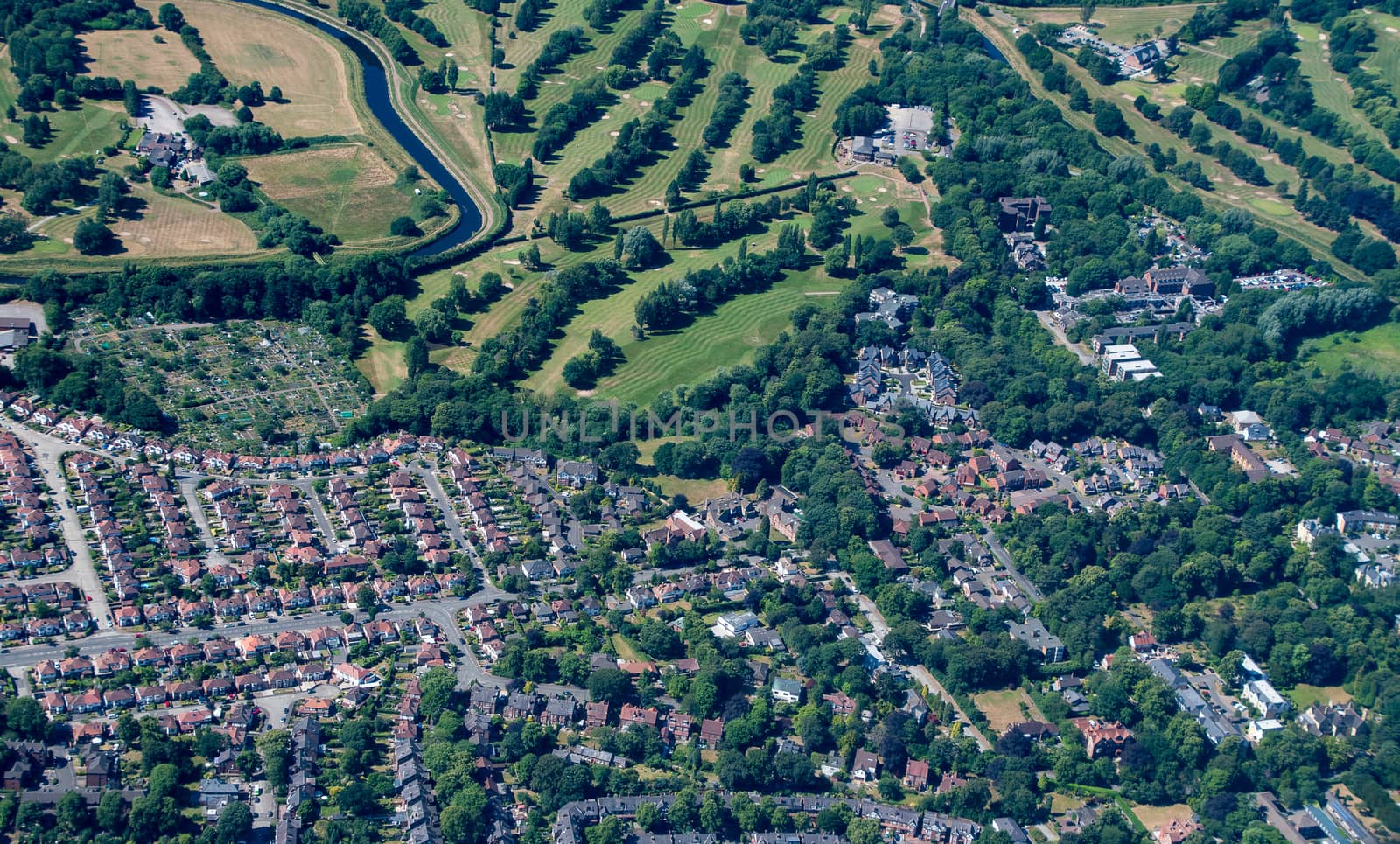 Aerial shot from a plane window of the English countryside showing town houses and part of a gold course